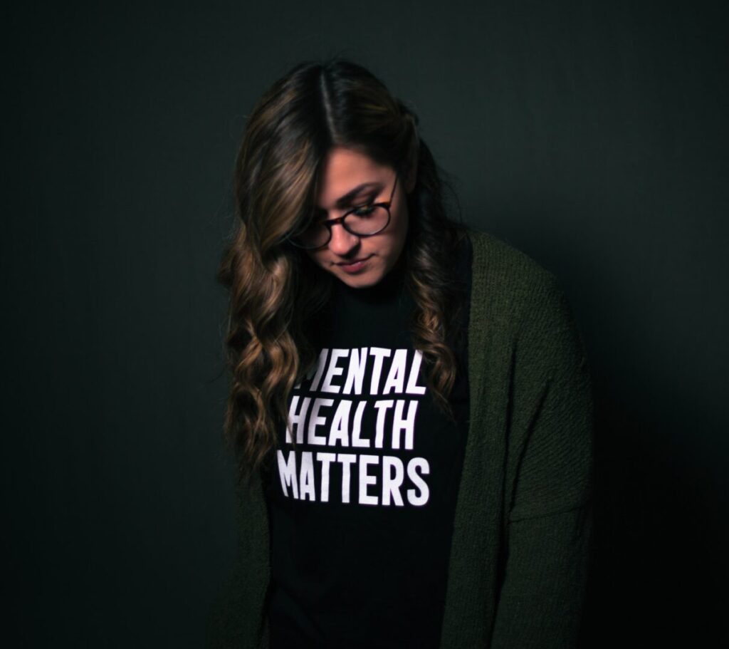 A woman wearing a black tee shirt with the words mental health matters on the front of it.