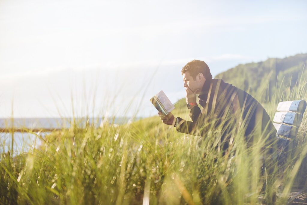 a man sitting in tall green grass reading a must-read health book