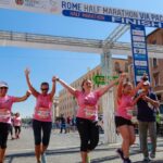 women crossing the finish line of a marathon with upraised arms celebrating cancer awareness and prevention wearing pink tee shirts