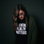 A woman wearing a black tee shirt with the words mental health matters on the front of it.