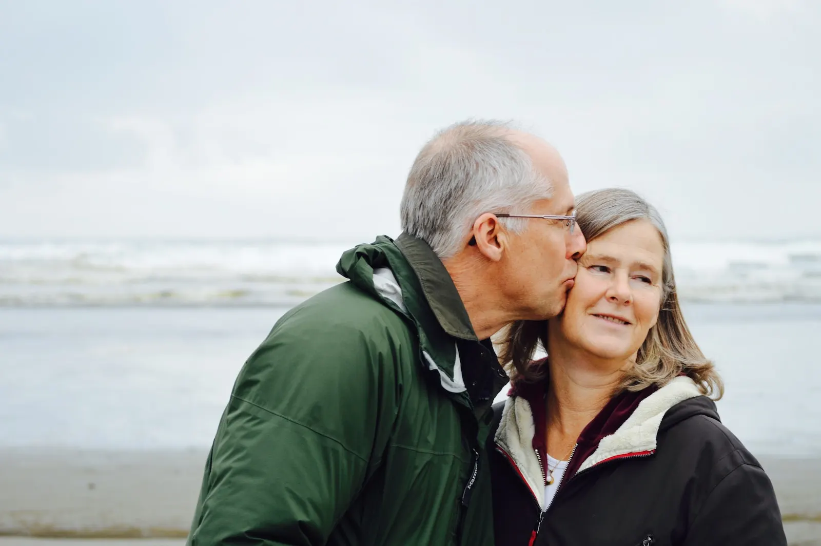 man kissing woman on check beside body of