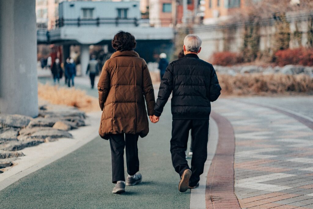 a husband and wife walking holding hands enjoying their golden years