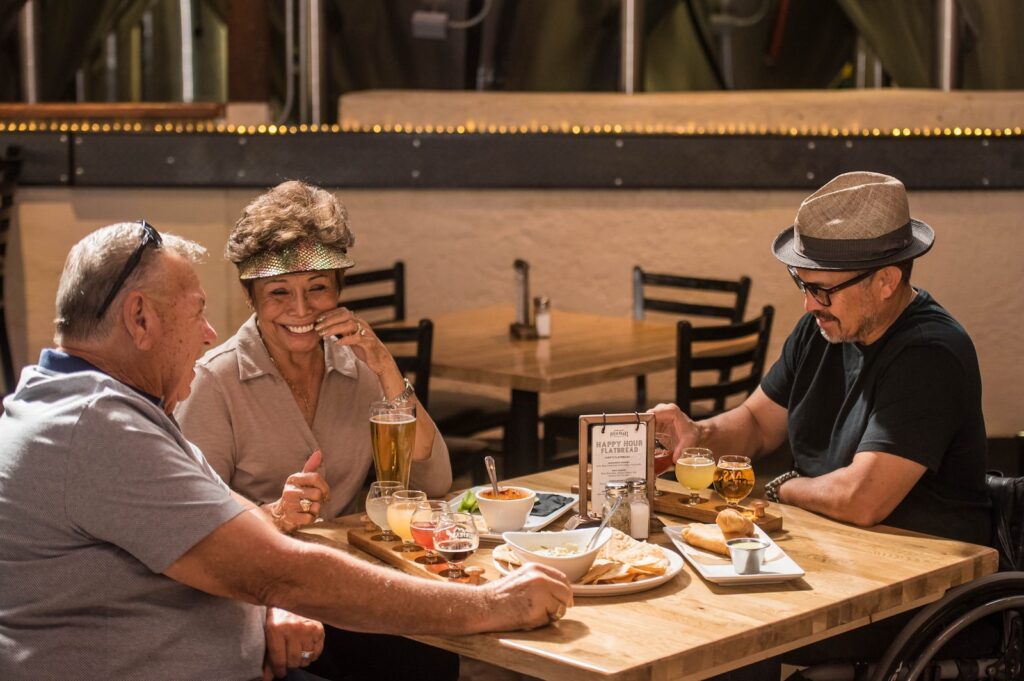 three seniors a women and two men enjoying drinks while healthy eating lunch