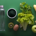 assorted fruits and vegetables and bottled water on a green surfa