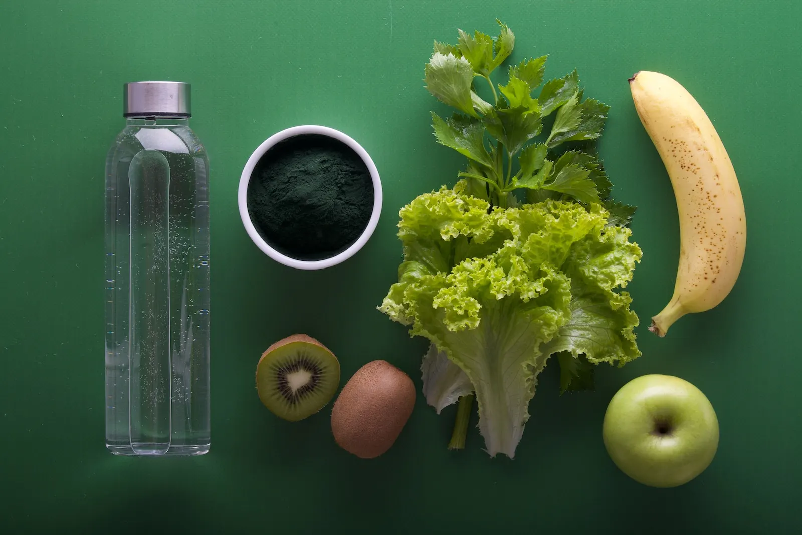 assorted fruits and vegetables and bottled water on a green surfa