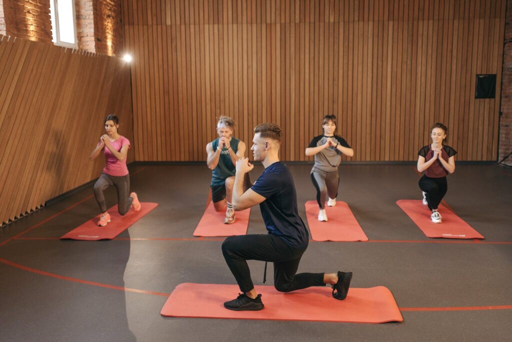 four students and instructor doing lunge exercises part of a balanced wellness living practices