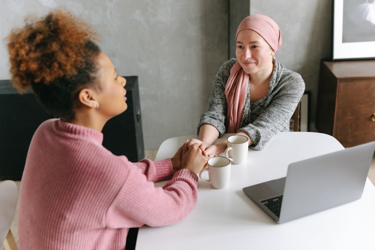 two women holding hands across a table projecting emotional wellness