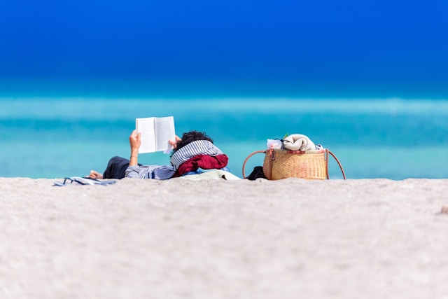 a women in the sand at the beach reading a must-read health book